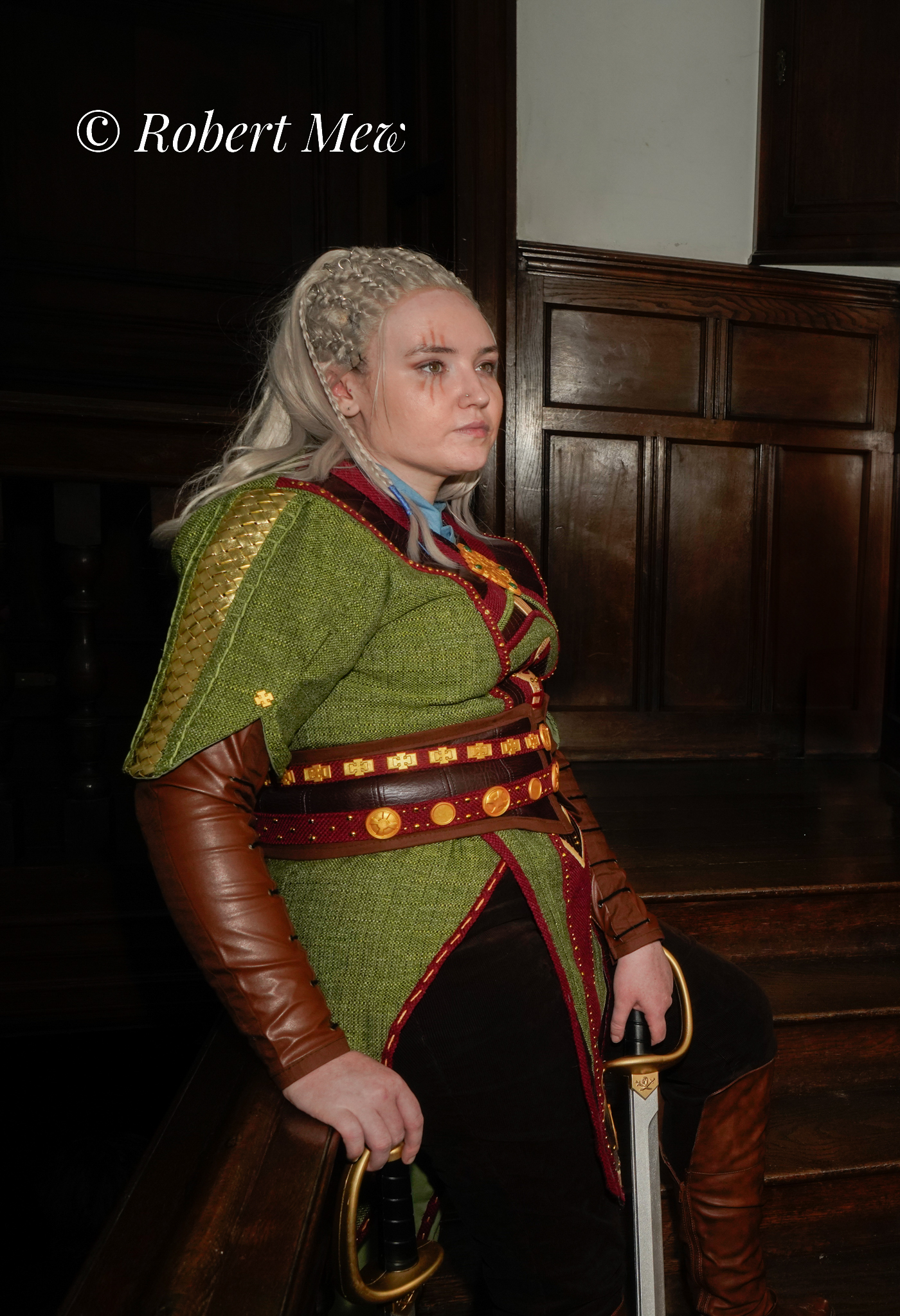 girl looks out with hilted sword and medieval costume